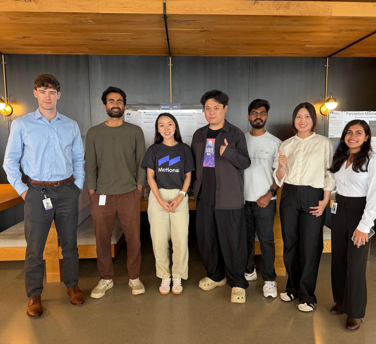 Varun Gandhi and six fellow interns standing together in front of research poster boards at Motional's poster presentation day